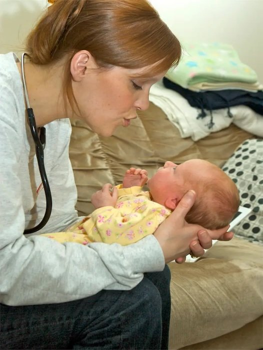 Nurse with stethoscope holding baby