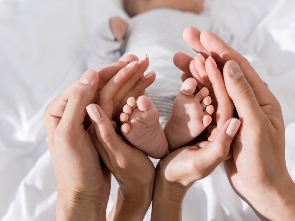 Baby feet wrapped in mom and dad's hands